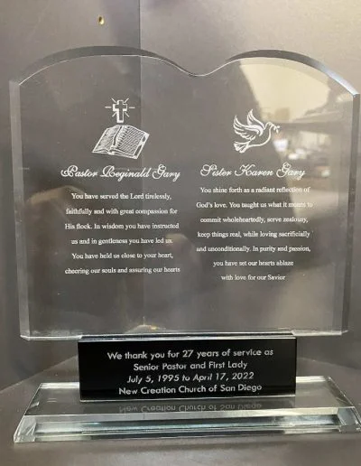 Clear glass plaque with inscriptions honoring pastors for 27 years of service at New Creation Church of San Diego.
