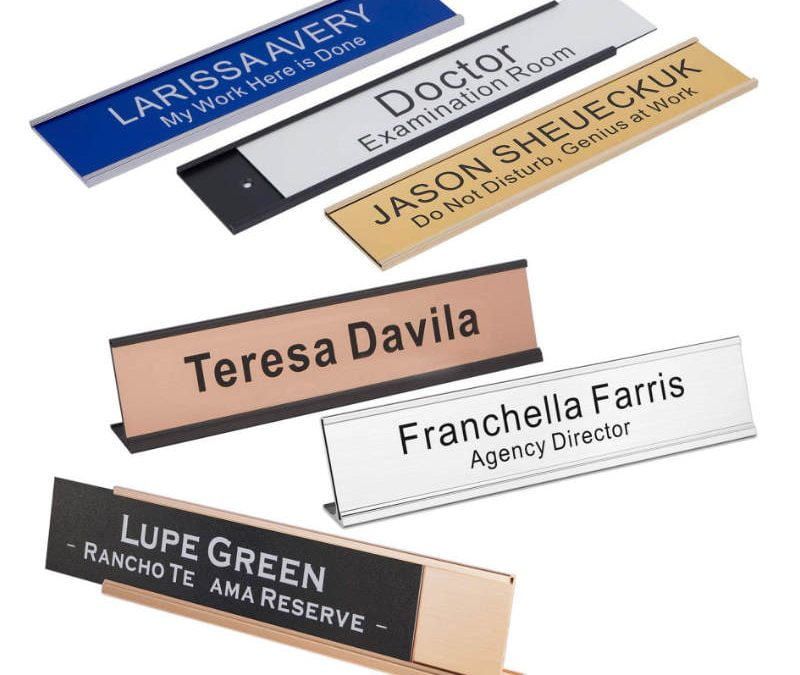 Six custom name badges with various names and titles in different colors and styles, displayed on stands.