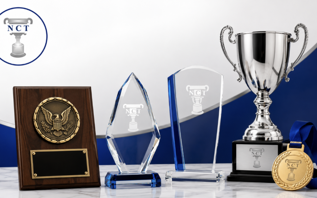 Four awards and a medal on a marble surface, featuring the NCT logo, with a blue and white background.